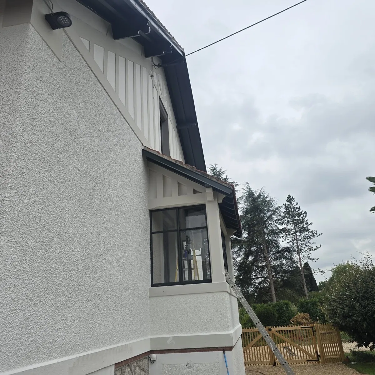 Pignon à colombages décoratifs et débords de toit repeints sur une villa