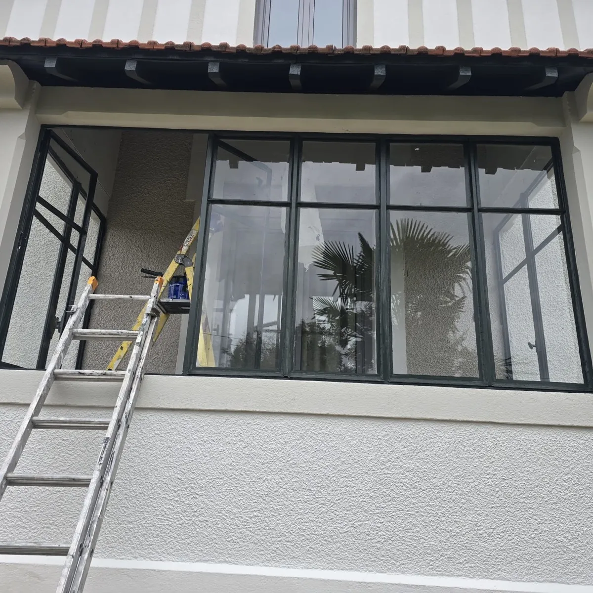 Verrière acier repeinte en noir sur une façade en cours de rénovation